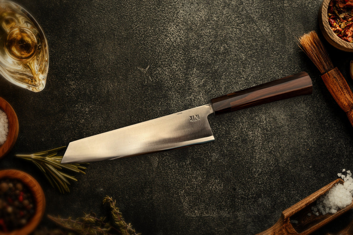 Couteau Chef Kiritsuke Forge Tay, finition inox, sur ardoise avec épices et herbes