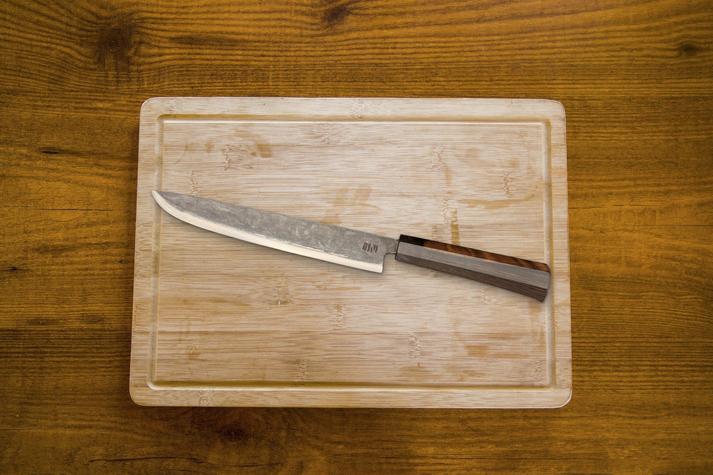 Couteau Fish trancheur Forge Tay, finition carbone noir, sur planche en bois
